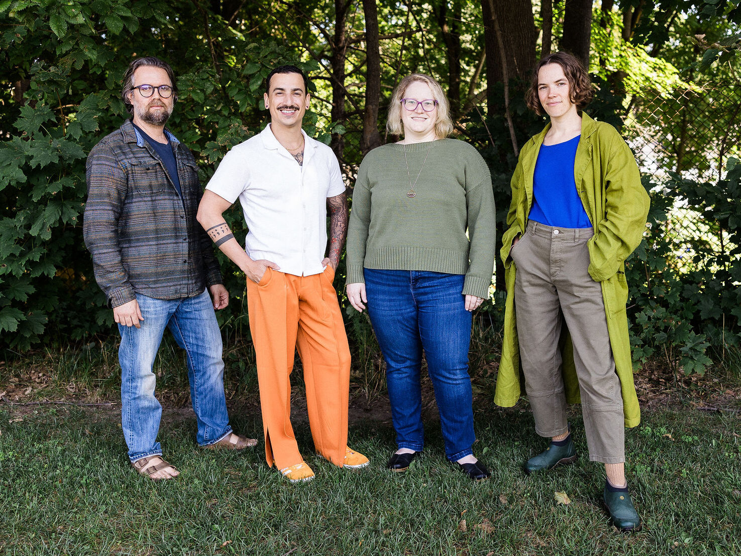 Four New Hires of 2024: Ryan Montella, Taurean Gagnon, Von Harvey, and Kate Sol standing close together and smiling under tree cover