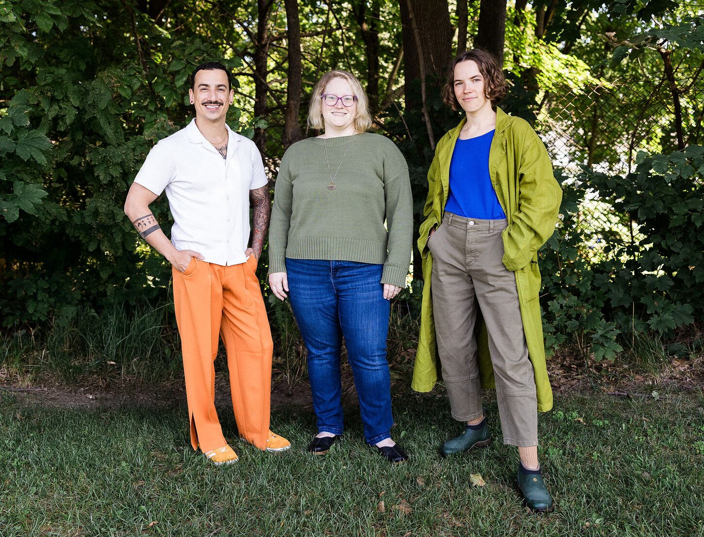 Three New Hires of 2024: Taurean Gagnon, Von Harvey, and Kate Sol standing close together and smiling under tree cover